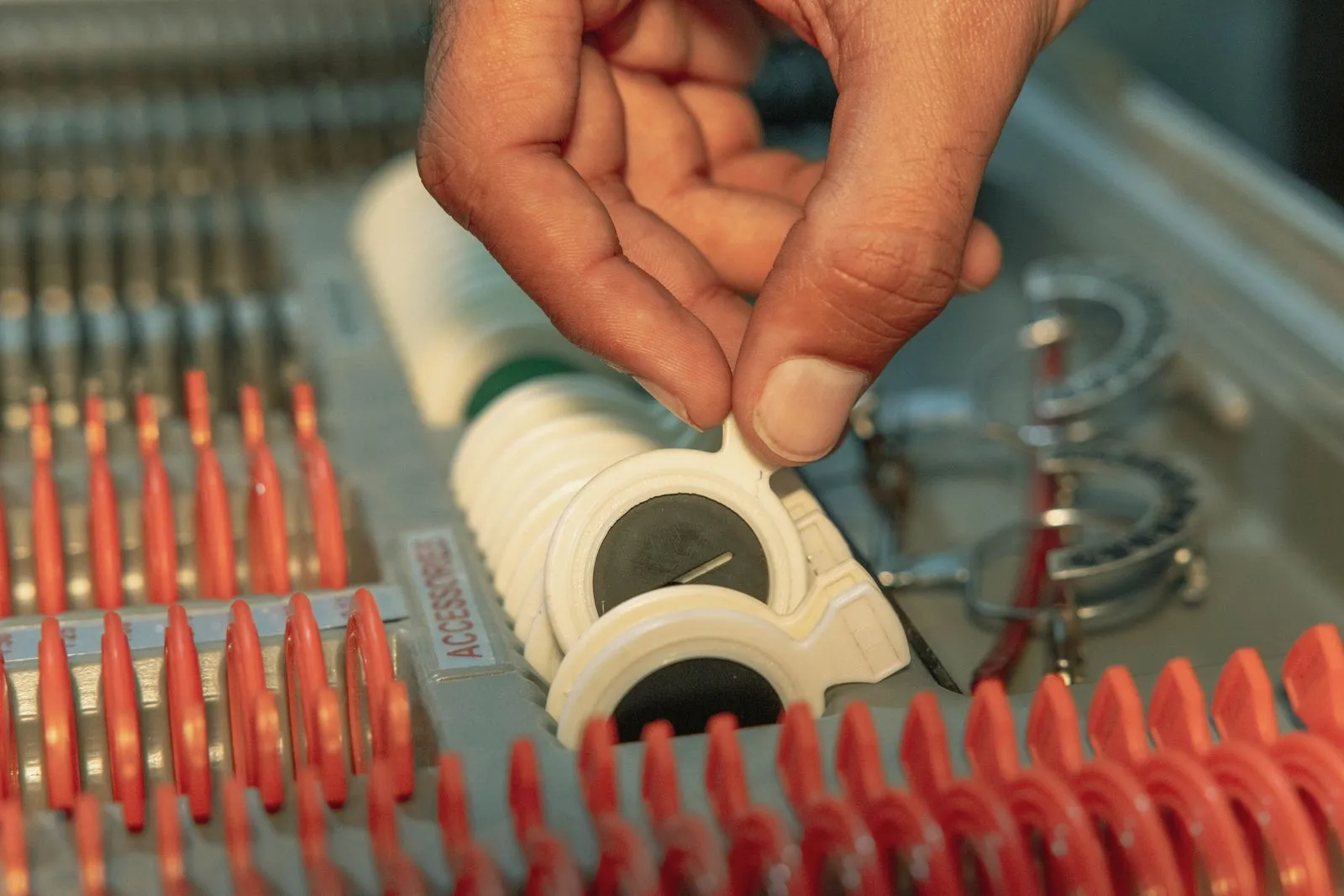 Detailed view of optometrist's hand choosing lens from optical kit, highlighting precision in eye care.